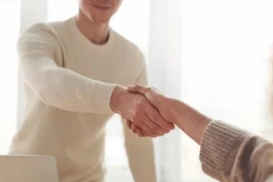 zwei Menschen, die sich die Hand geben über einem Tisch