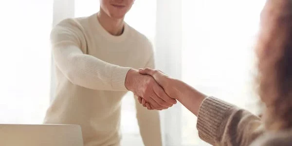 zwei Menschen, die sich die Hand geben über einem Tisch