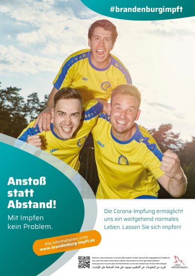 Impfkampagne. drei Männer in Fußballtshirts, lachen in die Kamera 