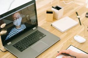 Interview über einen Computer mit einer Frau mit einer Maske