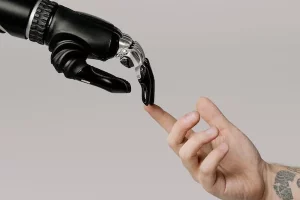 Eine männliche, tatoovierte Hand, die mit den Fingern eine robotter Hand berührt