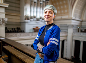 Motiv des Karriereportals "Steuer Deine Zukunft" der Brandenburger Finanzverwaltung: Junge Frau mit kurzen blondierten Haaren und dünner blauer Jacke steht in einem historischen Gebäude