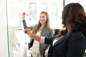 Zwei Frauen die an einem Whiteboard zusammen arbeiten