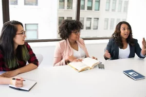Drei Frauen, sitzen an einem Tisch und führen eine Diskussion