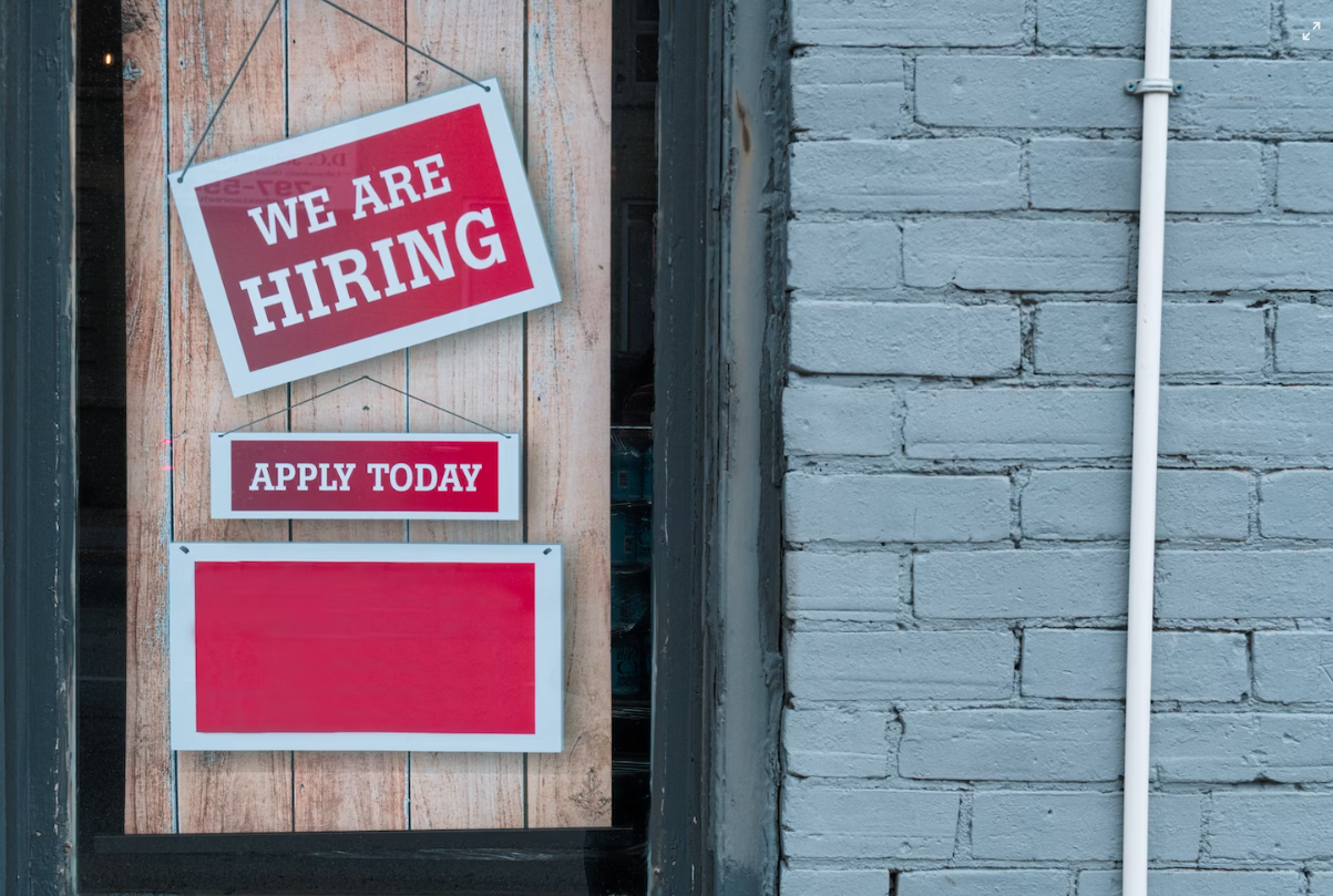 Zwei rote Schilder, auf denen in weißer Schrift "We are hiring" und "Apply" now steht