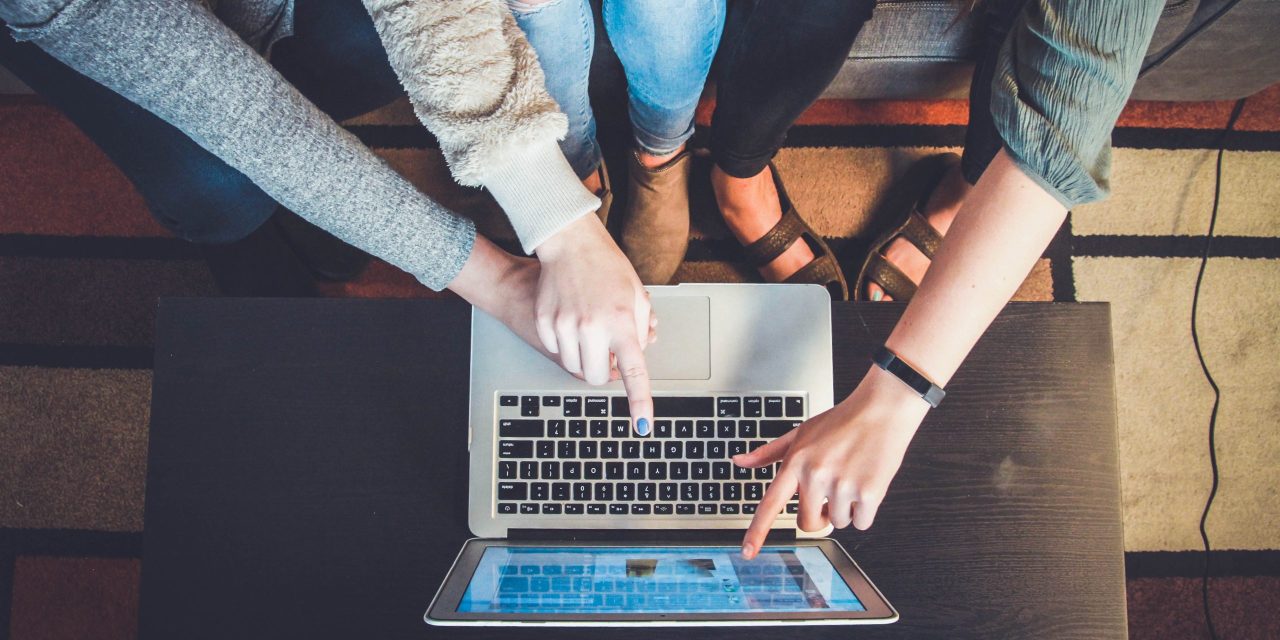 3 Frauen die auf einen Laptobbildschirm zeigen