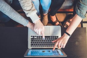 3 Frauen die auf einen Laptobbildschirm zeigen