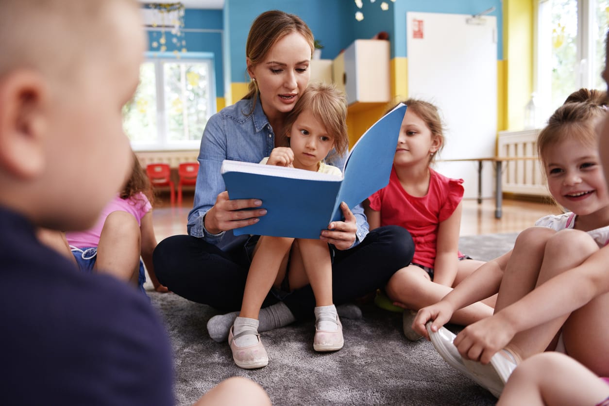 Erzieherin liest Kindern im Kindergarten eine Geschichte vor – Symbolbild für Stellenangebote im Bildungs- und Erziehungsbereich im Stellenmarktindikator September 2025.