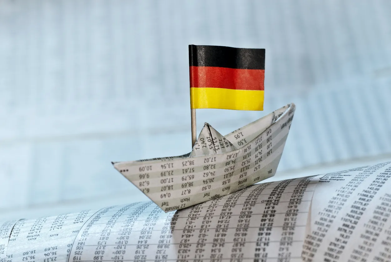 Papierschiffchen mit Deutschlandflagge auf Paper mit Zahlen