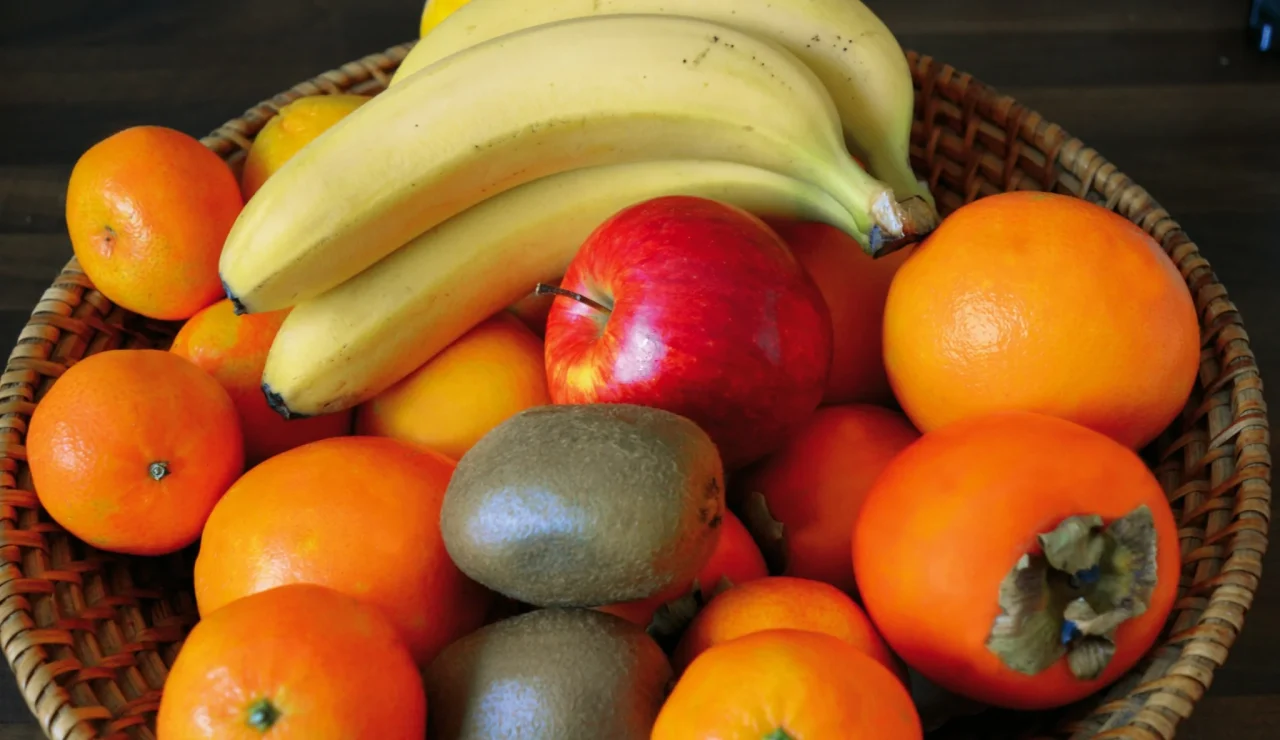 Geflochtener Obstkorb mit Bananen, Kiwis, Äpfel und Mandarinen